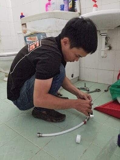Thợ đang lắp đặt một bộ xi phông mới cho chậu rửa mặt lavabo.