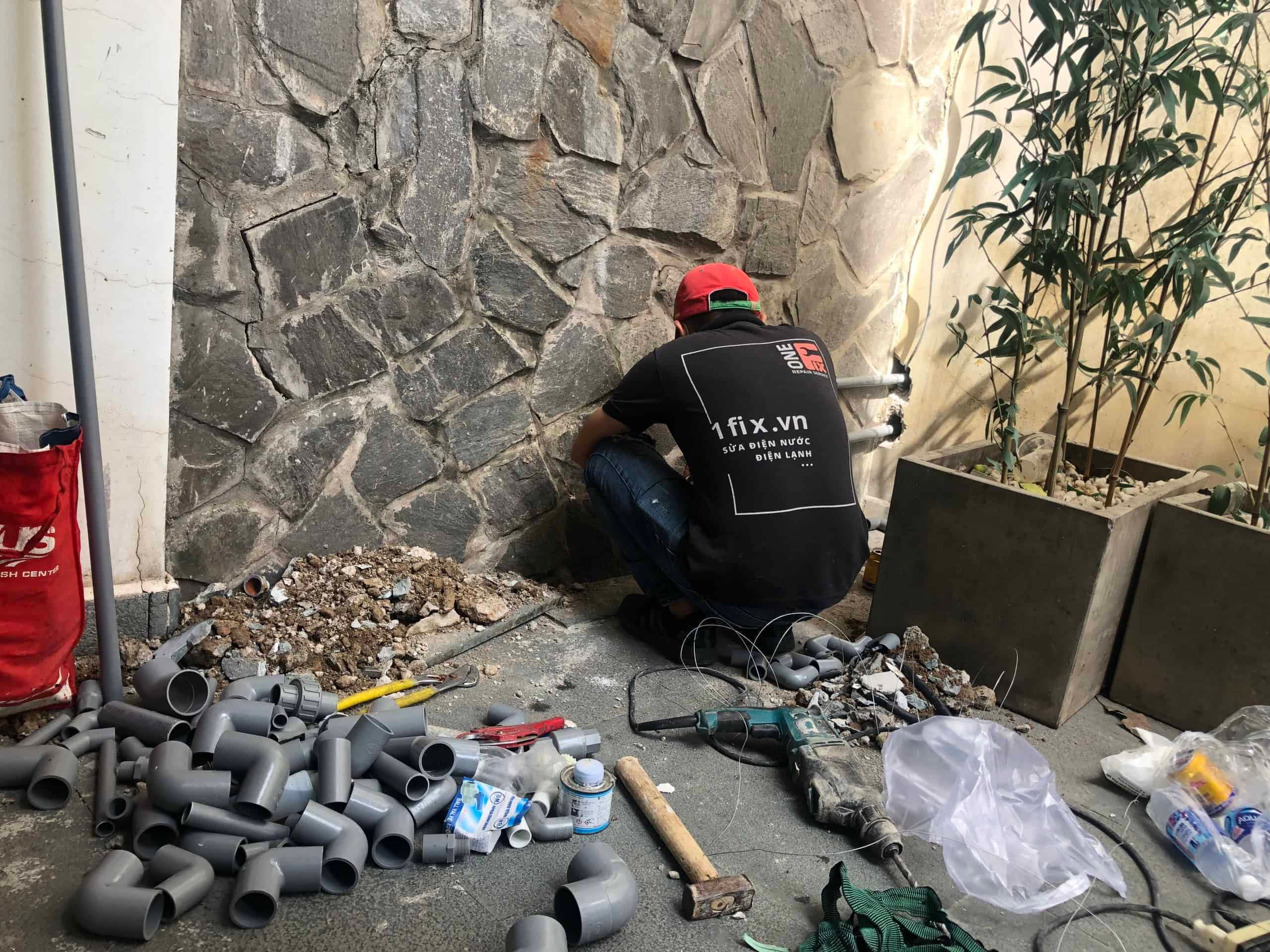 Thợ đang lắp đặt hệ thống giá đỡ và cố định máng xối nhựa vào vị trí.