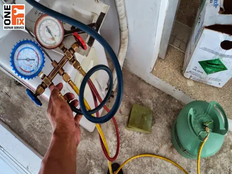 Tay thợ cầm bộ đồng hồ đo gas hai mặt xanh đỏ, dây vàng nối vào bình gas đặt dưới nền