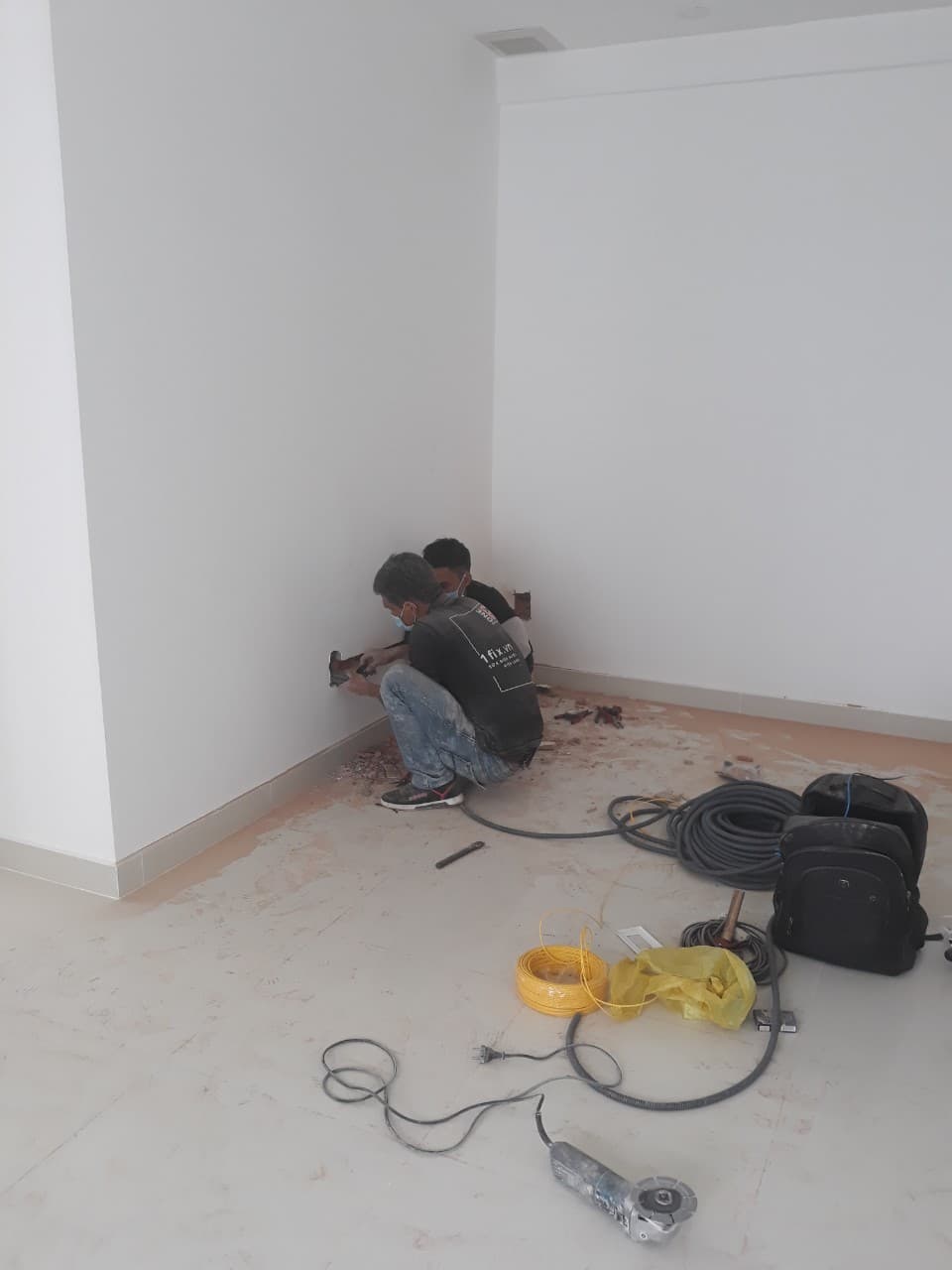 Thợ điện đang xác định vị trí và lên kế hoạch đi ống gen điện âm tường dựa trên bản vẽ.