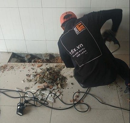 Thợ 1Fix đang đục sàn nhà vệ sinh để sửa ống nước bị bể âm