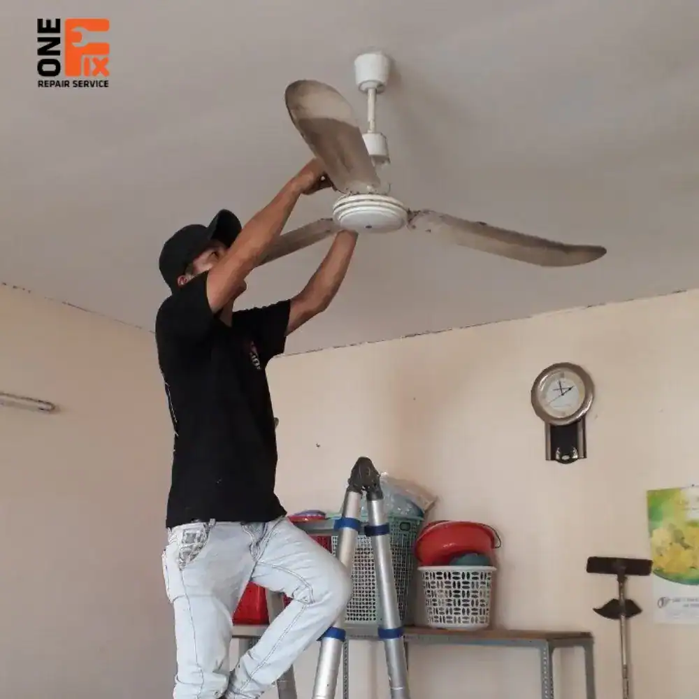 Thợ điện 1FIX đang thay tụ điện cho quạt trần để khắc phục tình trạng quạt chạy yếu